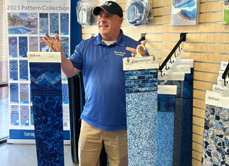 Employee holding different types of pool liners at Blue Wave Pools.